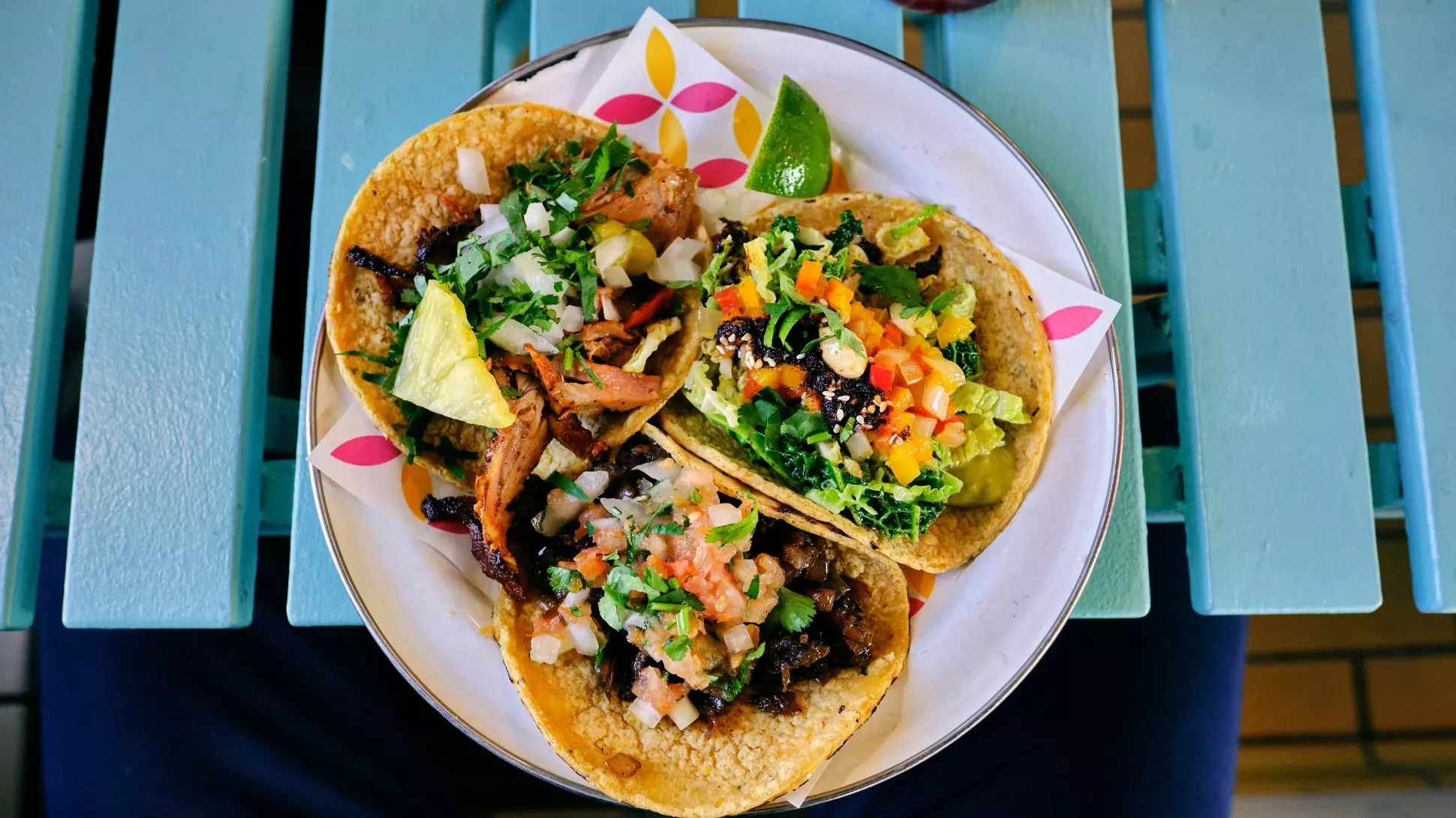 Agave Bar Three soft shell tacos on a plate on a blue picnic table