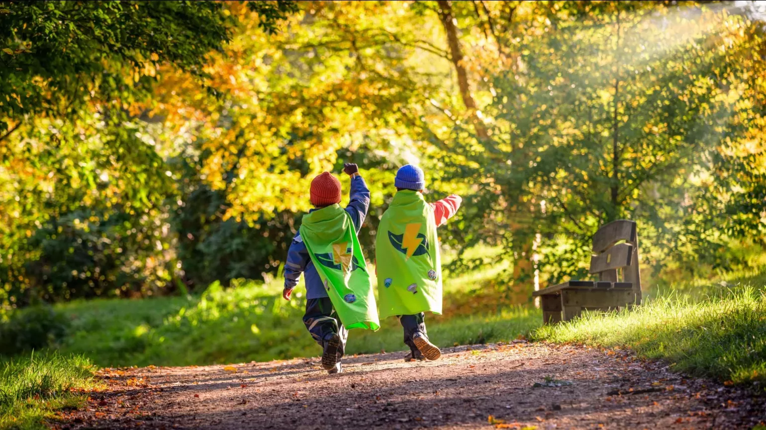 Nature Heroes at Wakehurst, Jim Holden © RBG Kew Two children in capes running through an autumnal landscape