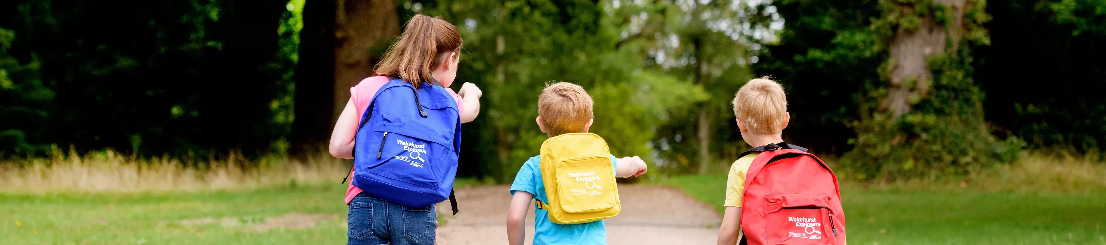 Explorer Rucksacks, Jim Holden © RBG Kew Three children walk down a forest path, each with a Wakehurst Explorer rucksack