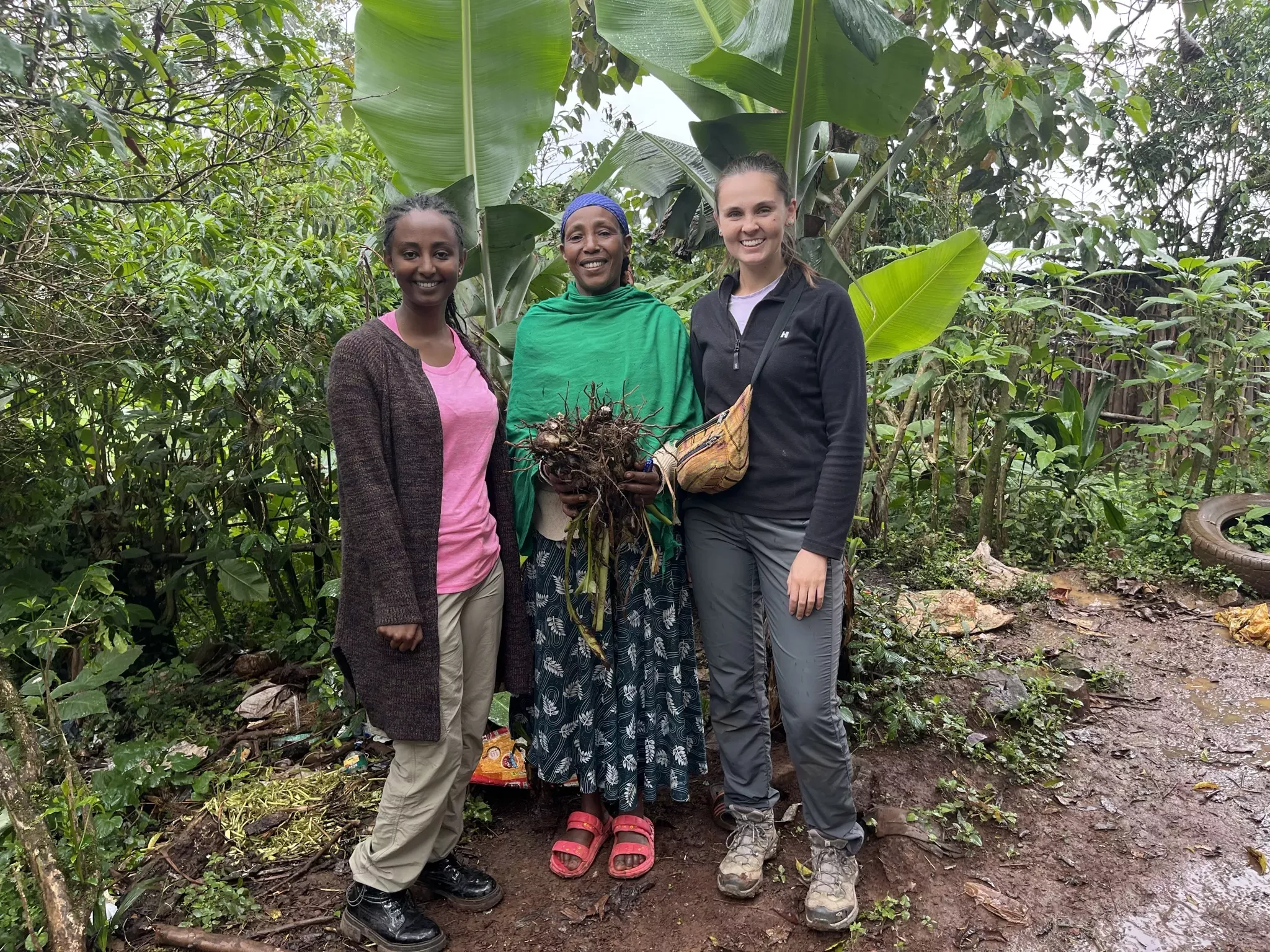 Two members of the project team Bezawit Genanaw (left) and Sophie Jago (right) stand with community member, Kesfanesh Mekuriya (centre), one of the women who expressed appreciation for being respected and included in the project's process © RBG Kew Three women stand infront of an enset plant