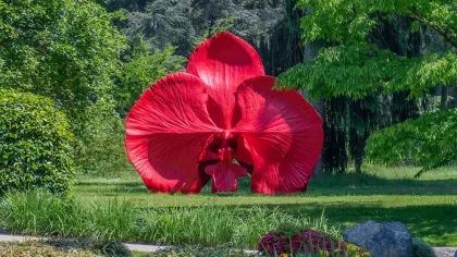 A large red orchid sculpture sitting in a green garden