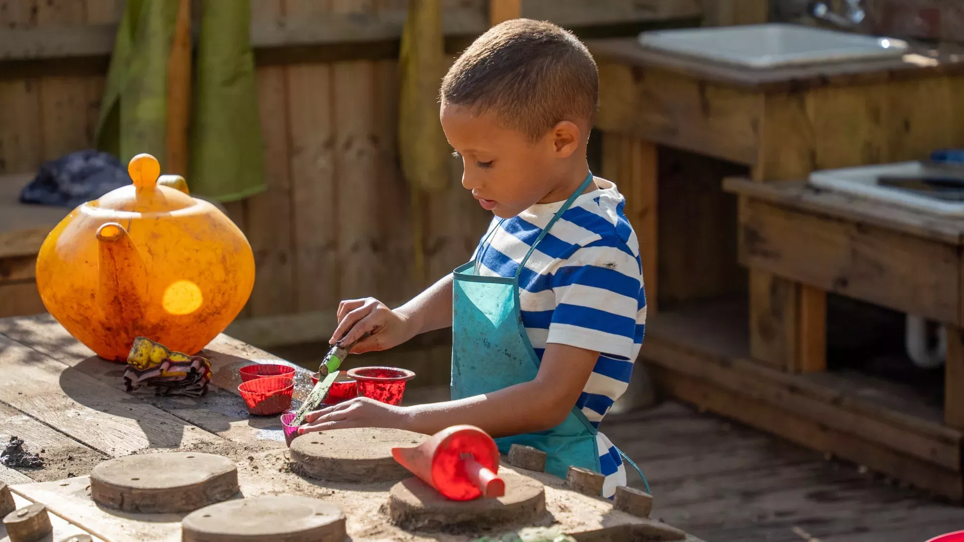 Mud Kitchen at Wakehurst, Visual Air © RBG Kew A young child plays with soil in a wooden kitchen
