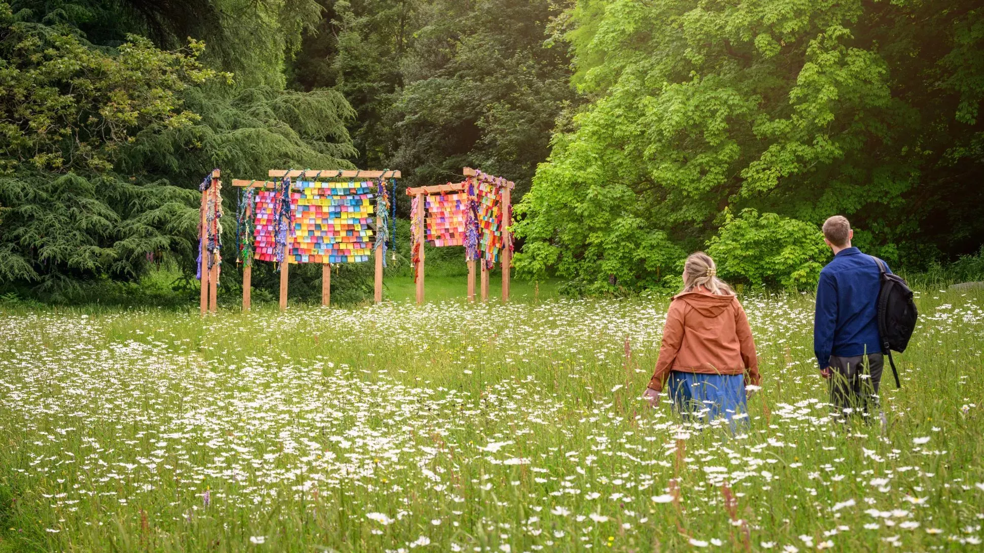 The Wings Flutter, Grasslands Are Alive by Saroj Patel, Jim Holden © RBG Kew Two people walkthrough a meadow with large wooden gates in the background