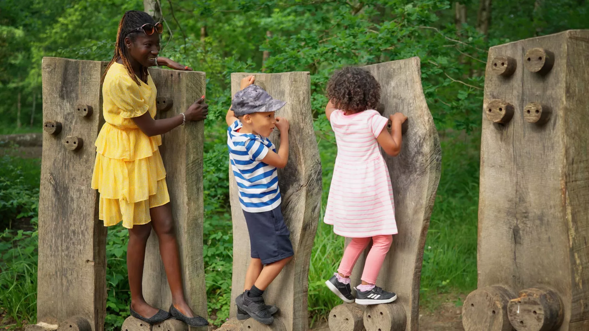 Tree Trunk Trek at Wakehurst, Visual Air © RBG Kew A family play on a set of logs in a forest